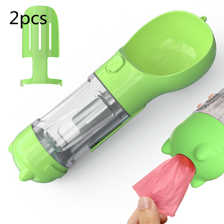 Portable green pet water bottle with built-in feeder bowl and garbage bag storage, ideal for outdoor travel.