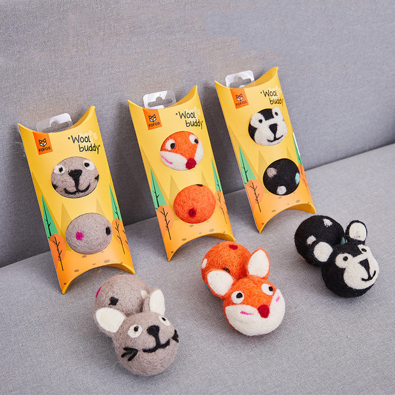 Colorful felt stretch ball cat toy with animal faces and packaging on gray surface.