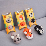 Colorful felt stretch ball cat toy with animal faces and packaging on gray surface.