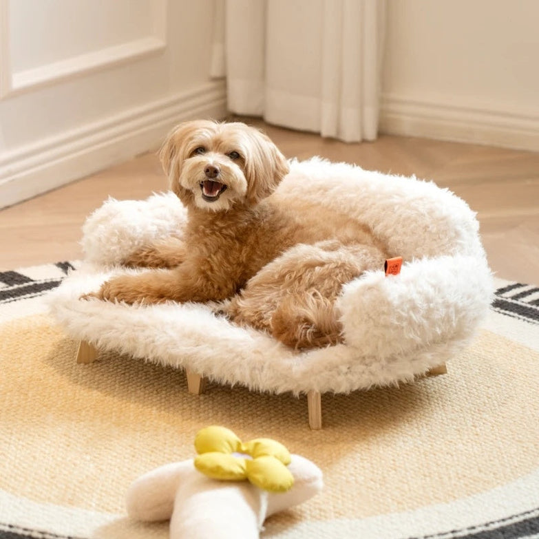 Small dog on a luxurious wooden pet bed with fluffy white fabric.