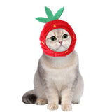 Cat wearing a red curly hair pet hat with green leaves, plush material.