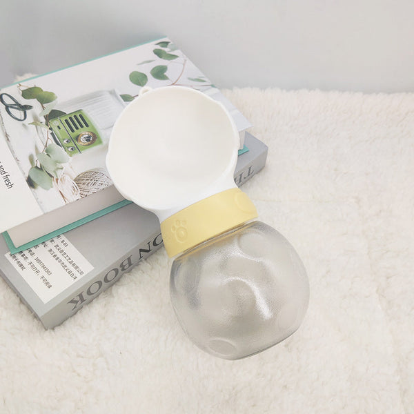 Portable dog water bottle with a bowl attachment on white fur background.